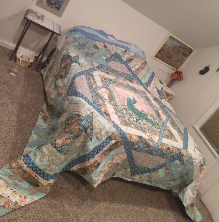 homemade king peacock quilt on queen bed